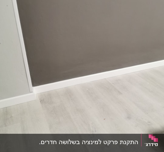 רצפת פרקט בהירה ליד קיר אפור